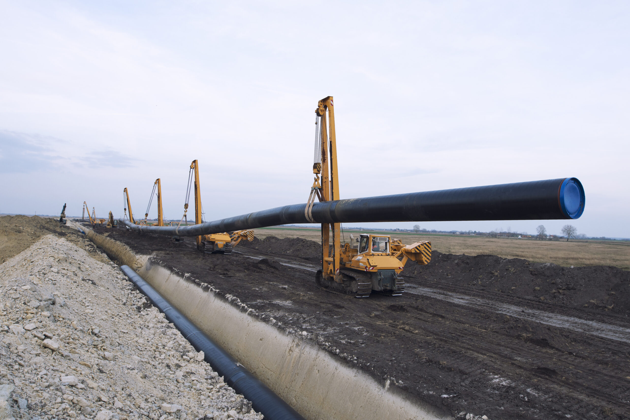 heavy duty construction machines carrying and placing gas pipe into the ground.
